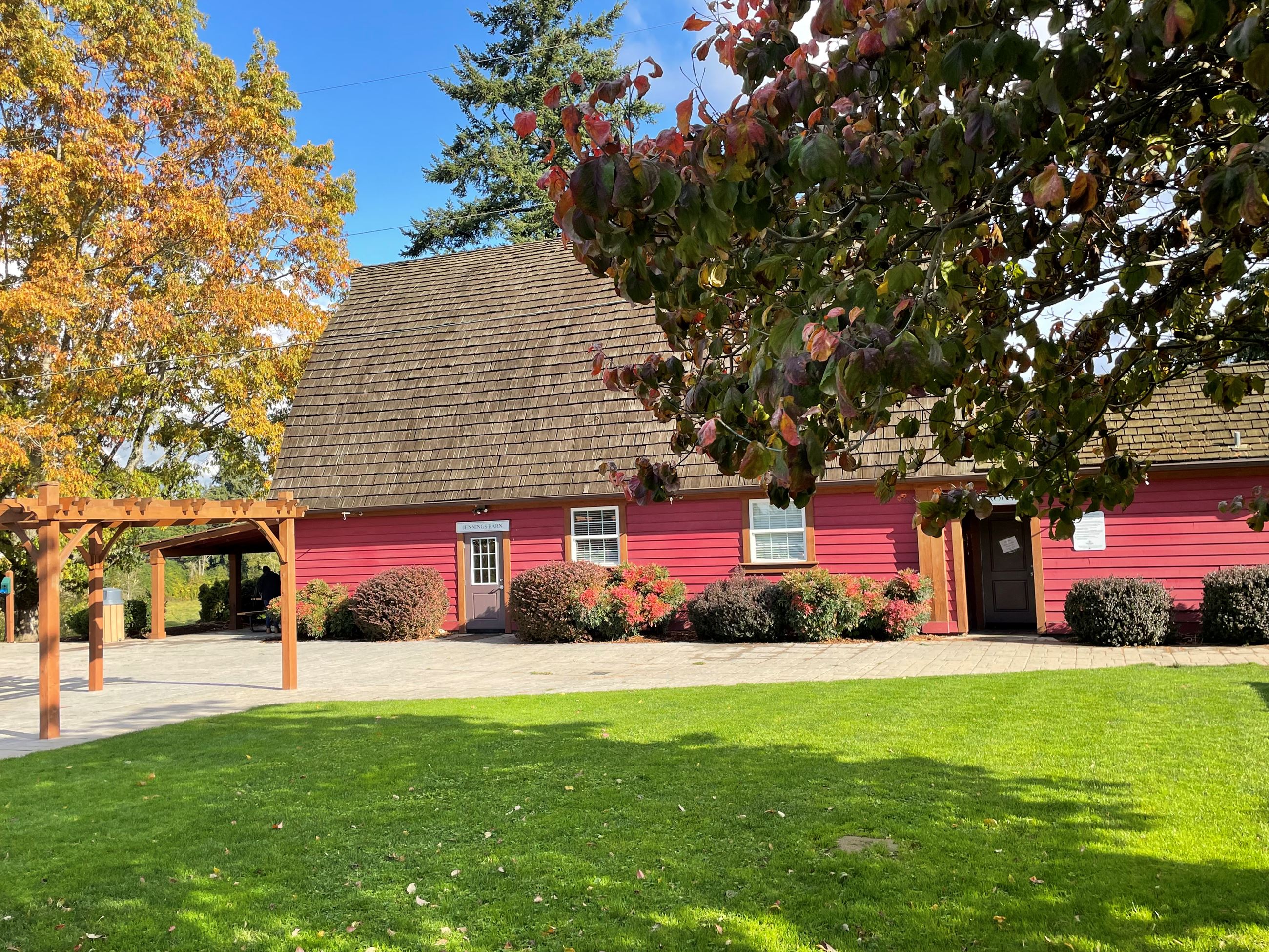 The Jennings Park Barn during summer weather, with a tree in the background.