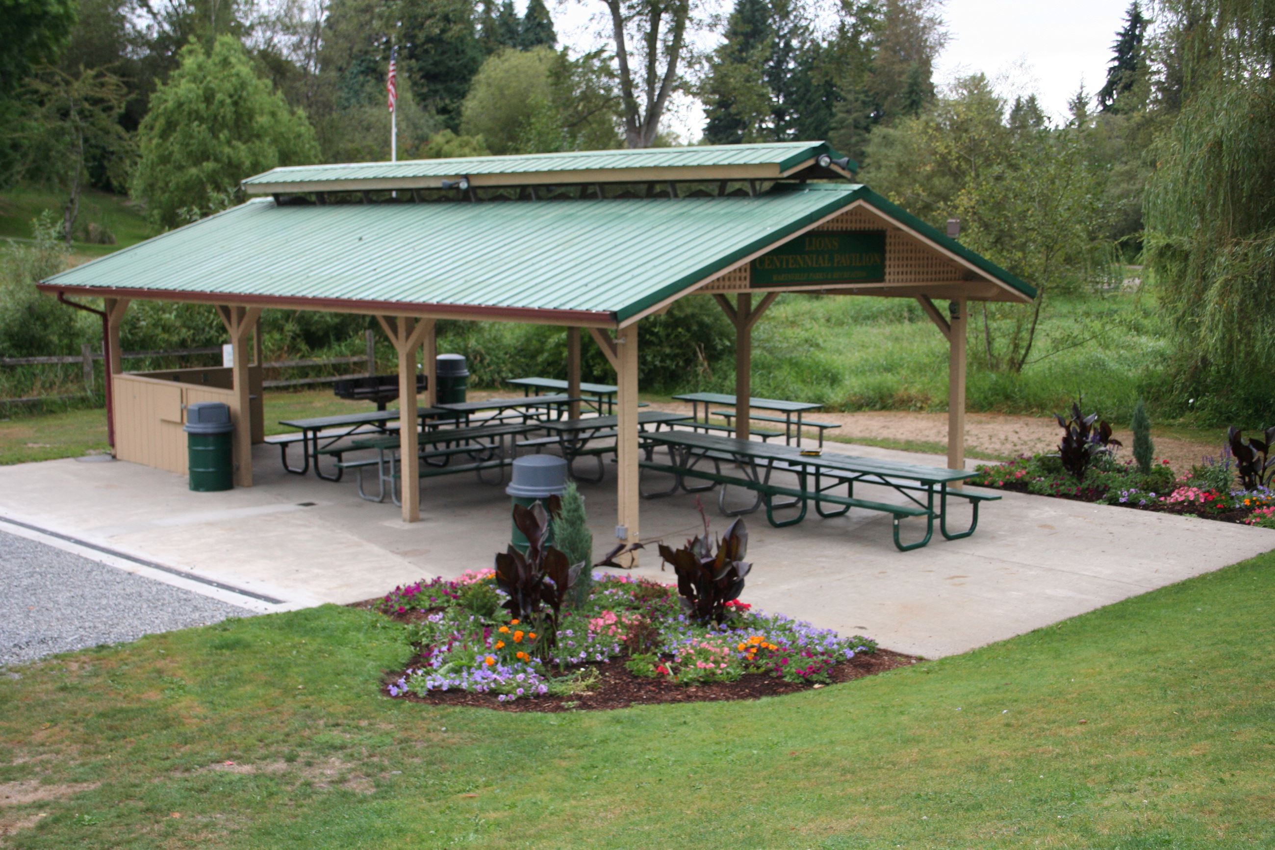 The Lions Pavilion is shown during fair, dry weather. A flower bed can be seen near it.
