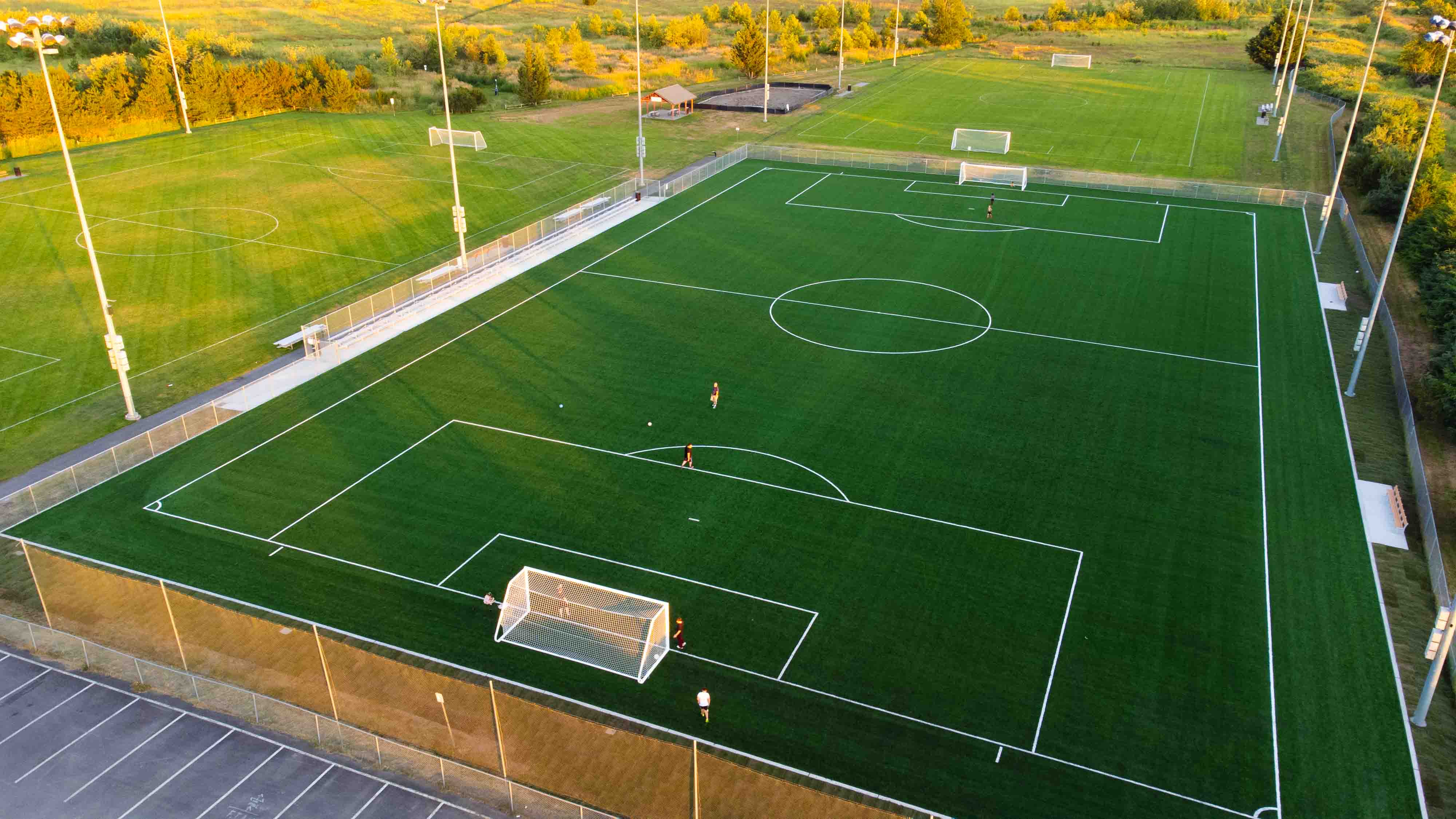 The turf field at Strawberry Field Athletic Park from a frontal aerial view during sunset.