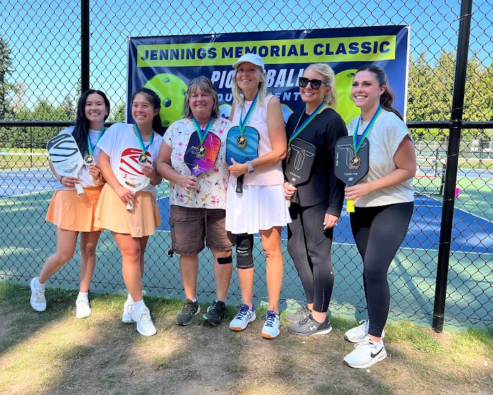 A group of 6 women posing with their medals and pickleball paddles at the Jennings Memorial Park .