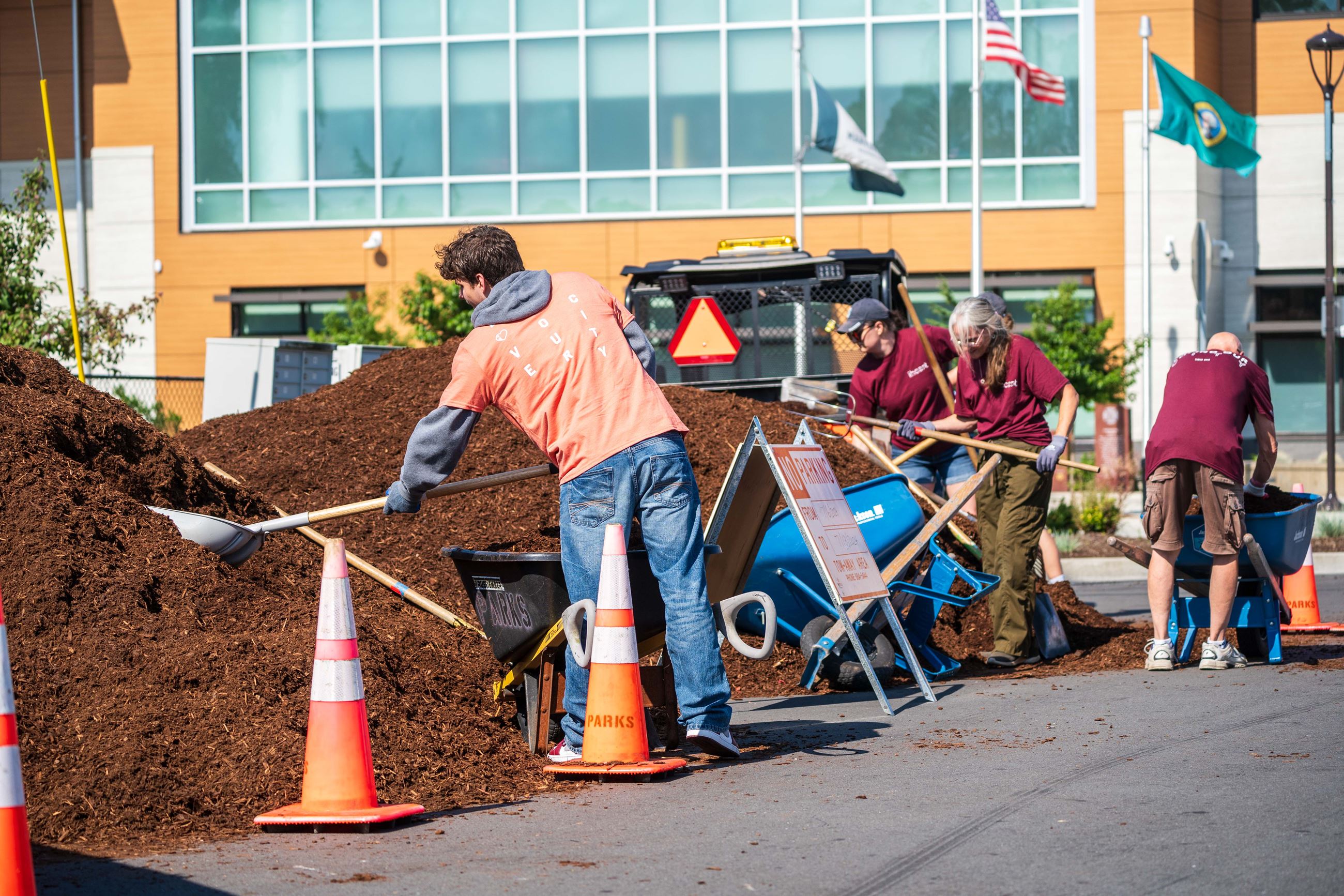 Volunteers shoveling bark chips outside city hall.