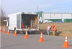 Utility workers performing hydrant maintenance. City vehicle and safety cones visible.